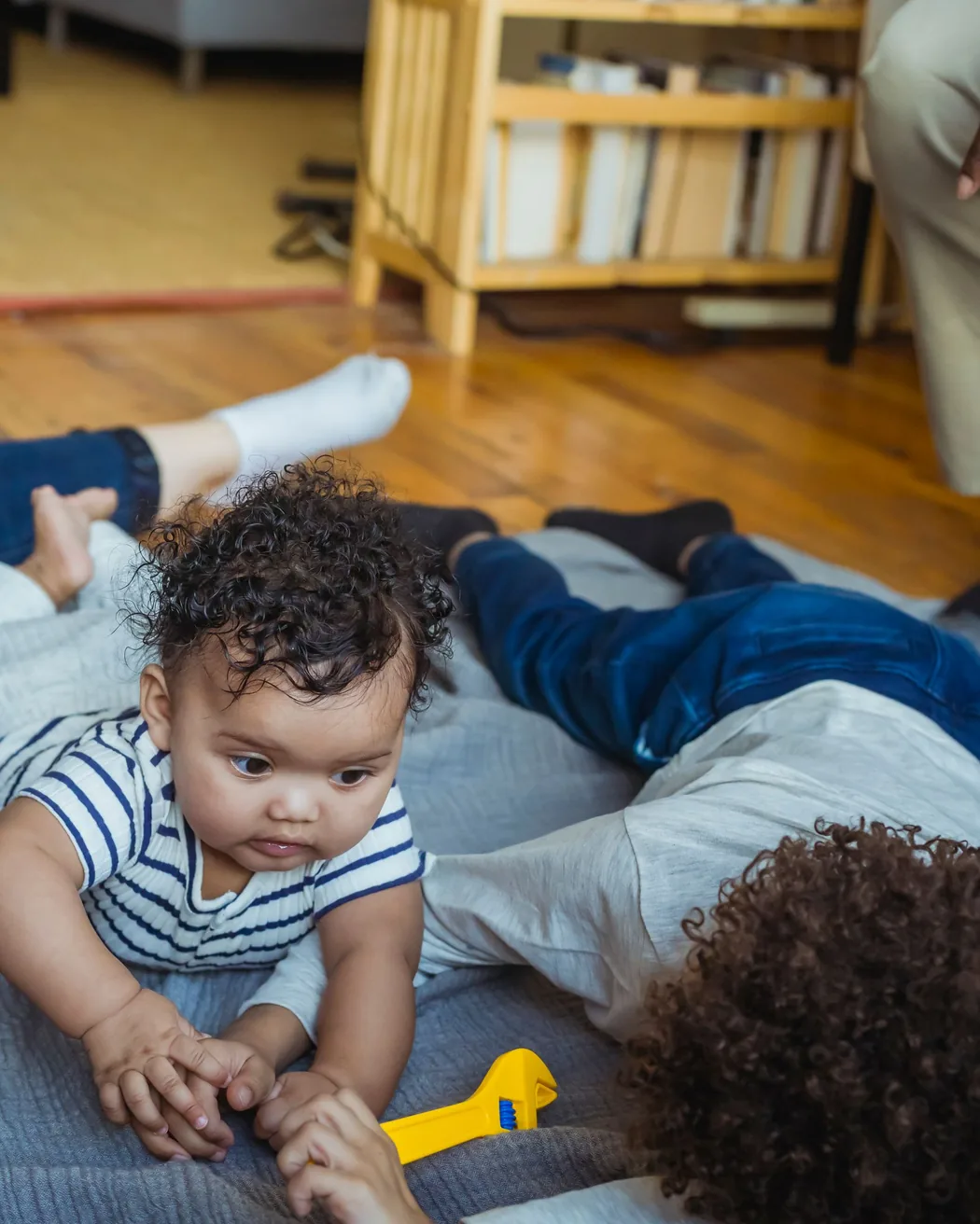 A baby exploring with siblings on a play mat