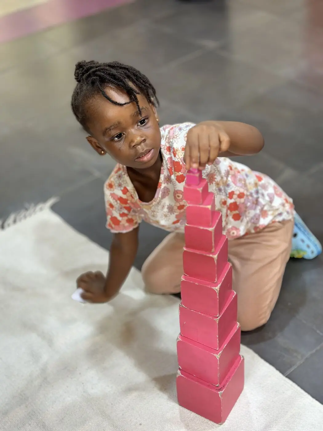 A Toddler child working with the Montessori pink tower