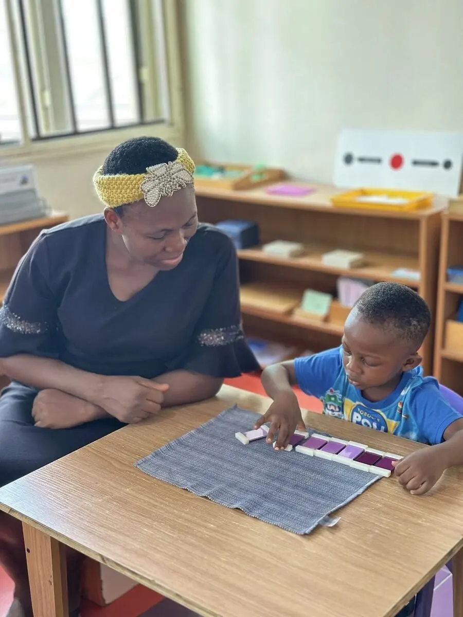 An AMI-certified guide sitting beside a child at Aquila Nidus