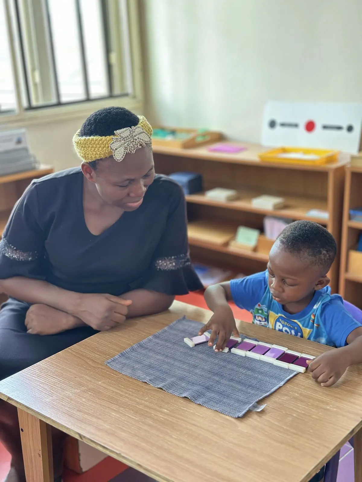 An AMI-trained guide working closely with a child at Aquila Nidus