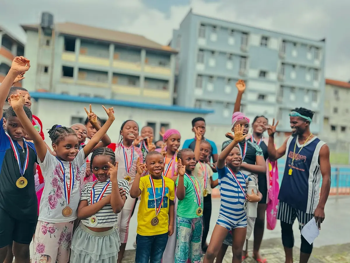 A large group of children cheering in the school courtyard, wearing medals